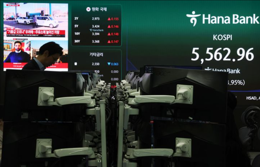 Hana Bank trading floor displaying KOSPI at 5,562.96, down 3.95%, with news coverage of the Iran conflict visible on background screens