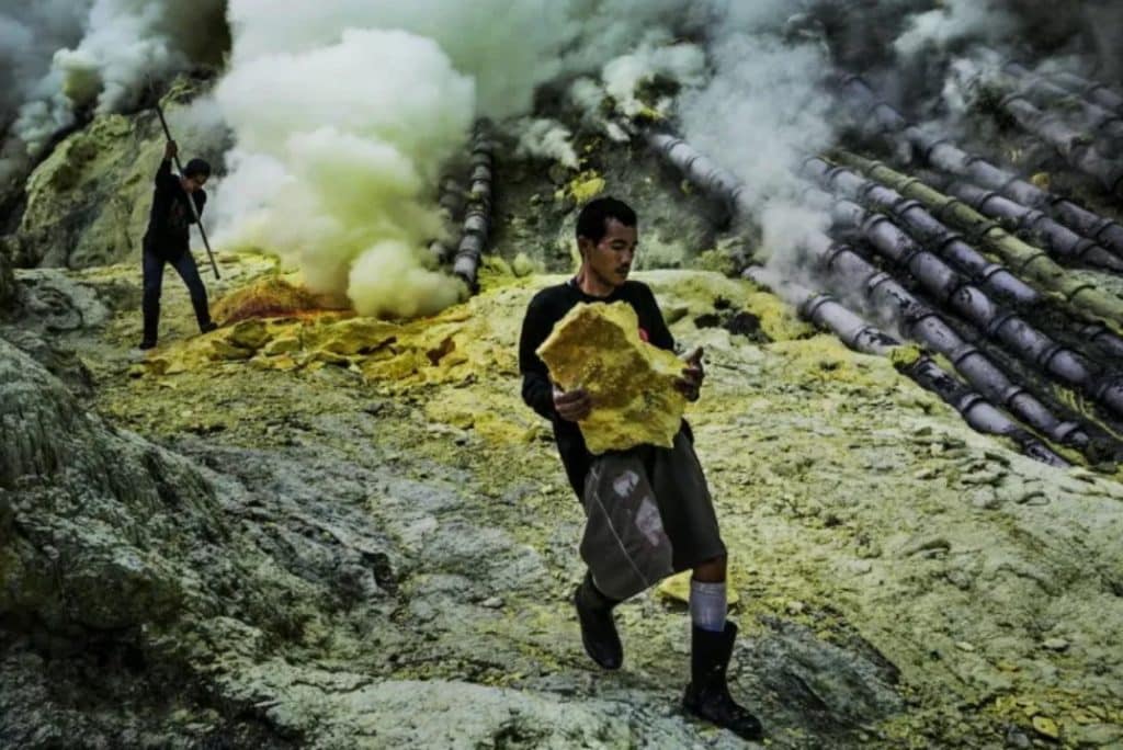 A miner carries a large chunk of high-purity sulphur with his bare hands