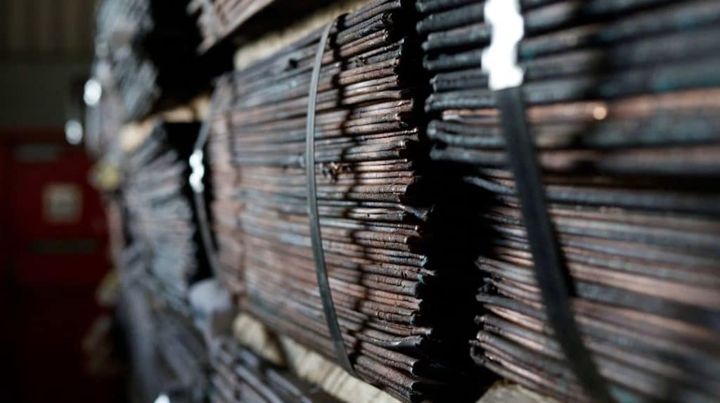 Stacked copper cathode sheets bound with metal straps in a warehouse awaiting export