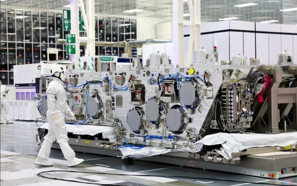 worker in cleanroom suit walking past a large ASML lithography machine on the production floor China chip breakthrough