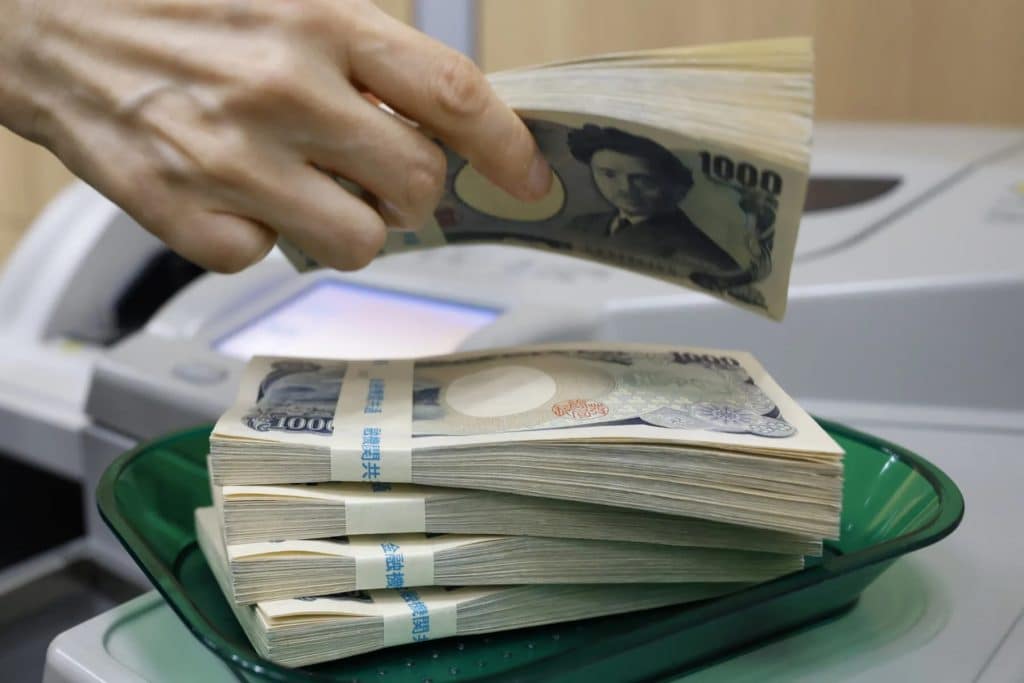 A person counting Yen currency with machine amid volatility
