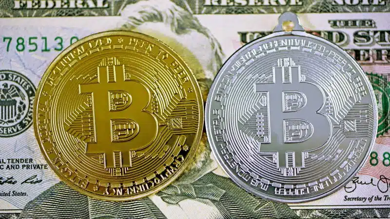 Bitcoin policy risk image showing gold and silver Bitcoin coins on US dollar highlighting Bitcoin price Bitcoin regulatory risk US voter poll and voter government stakes