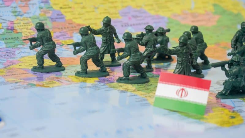 Military figurines on a map symbolize rising US-Iran war tensions and their impact on the Strait of Hormuz, global oil trade, and oil supply