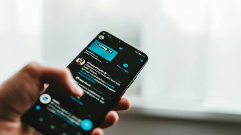 Hand holding a smartphone displaying X, representing X crypto trading, X USDC payments, X creator payments, and potential X crypto buy sell features.
