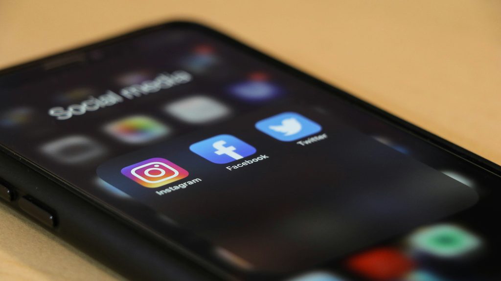 Smartphone showing social media apps, representing Elon Musk X and its expansion into X crypto trading, X USDC payments, X creator payments, and X crypto buy sell features.