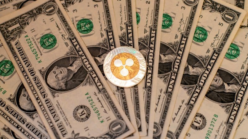 An XRP coin rests on US dollar bills, highlighting XRP ETF inflows, Goldman Sachs XRP exposure, rising XRP interest, XRP ETF institutional holders, and institutional XRP exposure.